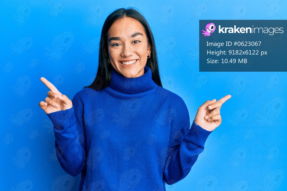 Young asian woman wearing casual winter sweater smiling confident pointing with fingers to different directions. copy space for advertisement 