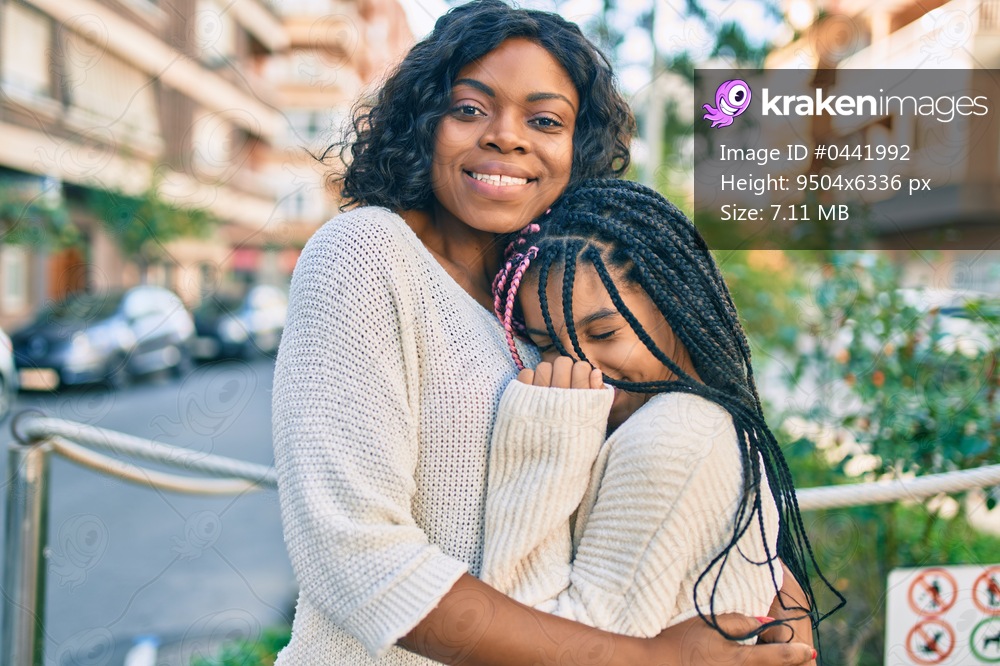 Beautiful african american mother and daughter smiling happy and hugging. Standing with smile on face standing at the park.