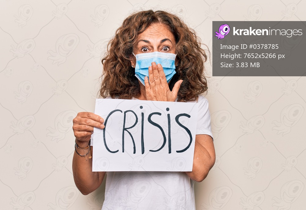 Middle age woman wearing coronavirus protection mask holding epidemic crisis paper as protest covering mouth with hand, shocked and afraid for mistake. Surprised expression