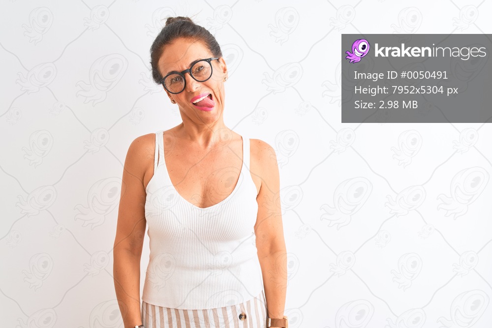 Middle age woman wearing casual t-shirt and glasses standing over isolated white background sticking tongue out happy with funny expression. Emotion concept.