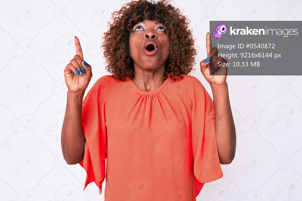 Young african american woman wearing casual clothes amazed and surprised looking up and pointing with fingers and raised arms. 