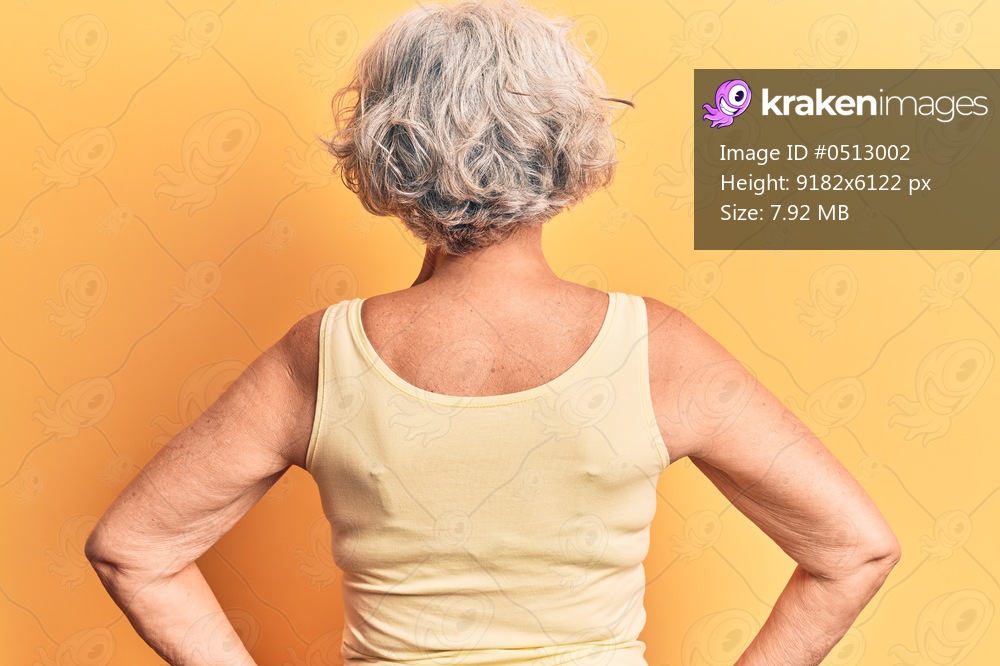 Senior grey-haired woman wearing casual clothes standing backwards looking away with arms on body 