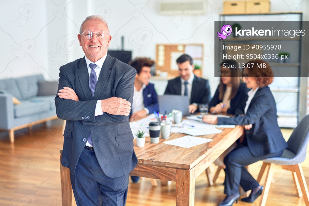 Group of business workers smiling happy and confident working together in a meeting. One of them, standing with smile on face looking at camera at the office.