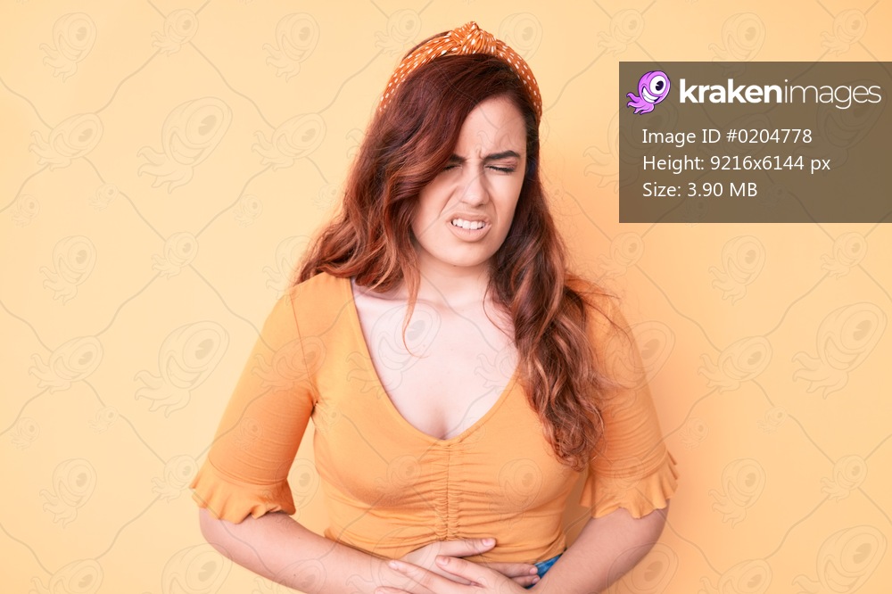 Young beautiful woman wearing casual clothes with hand on stomach because nausea, painful disease feeling unwell. ache concept. 