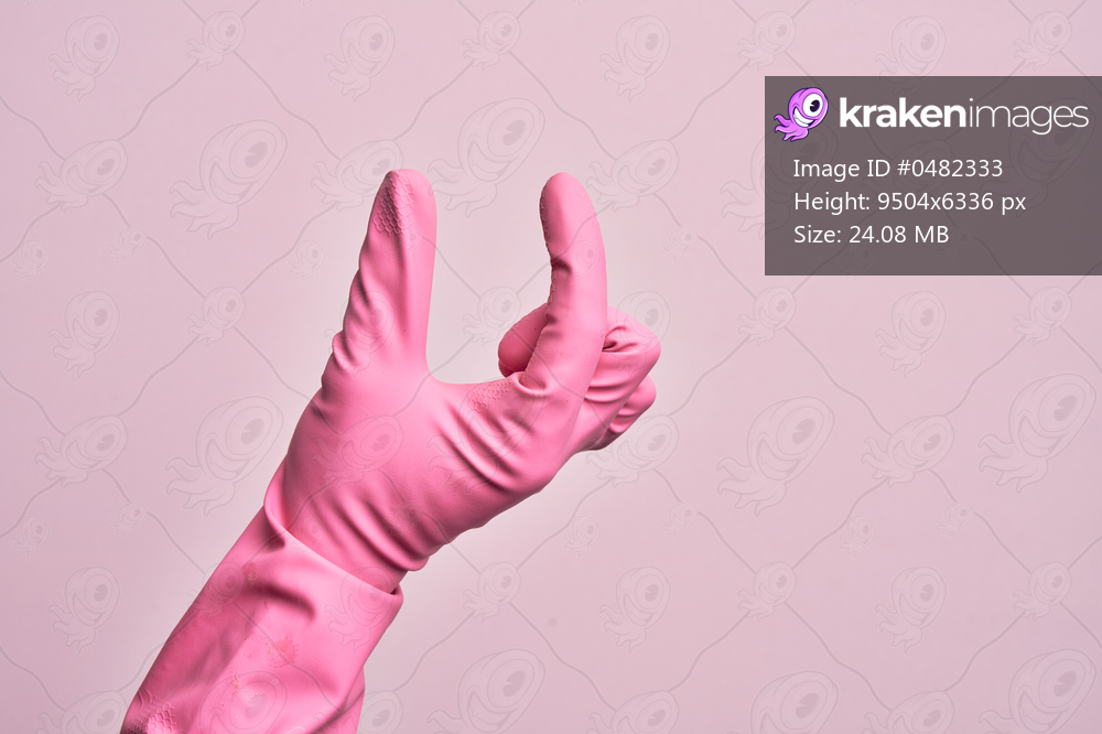 Hand of caucasian young man with cleaning glove over isolated pink background picking and taking invisible thing, holding object with fingers showing space