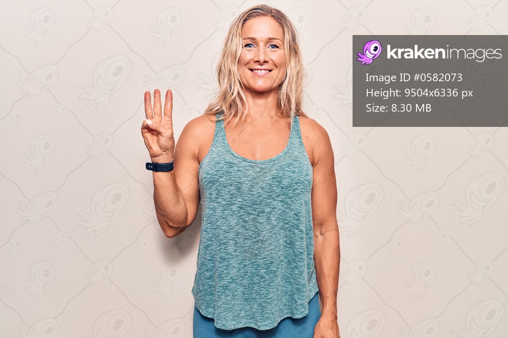 Middle age caucasian blonde woman wearing sportswear showing and pointing up with fingers number three while smiling confident and happy. 