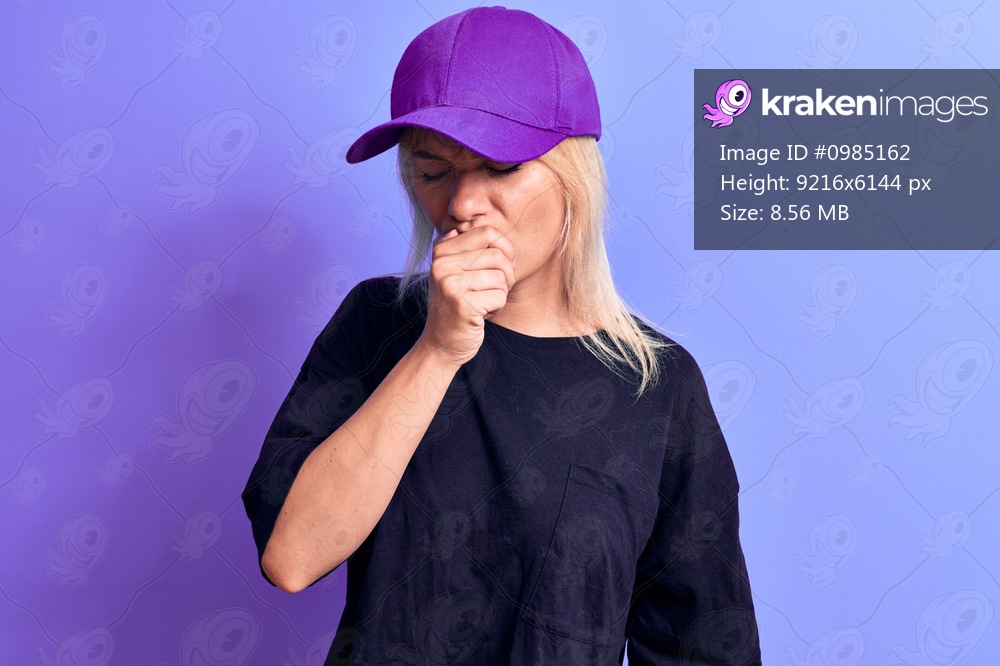 Young beautiful blonde woman wearing t-shirt and purple cap over isolated background feeling unwell and coughing as symptom for cold or bronchitis. Health care concept.