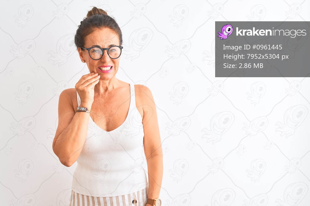 Middle age woman wearing casual t-shirt and glasses standing over isolated white background touching mouth with hand with painful expression because of toothache or dental illness on teeth. Dentist concept.