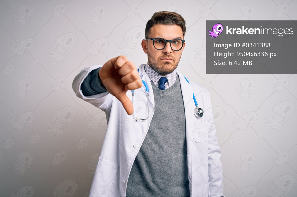 Young doctor man with blue eyes wearing medical coat and stethoscope over isolated background looking unhappy and angry showing rejection and negative with thumbs down gesture. Bad expression.
