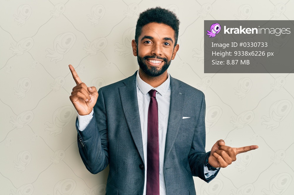 Handsome hispanic man with beard wearing business suit and tie smiling confident pointing with fingers to different directions. copy space for advertisement 