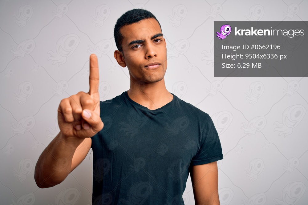 Young handsome african american man wearing casual t-shirt standing over white background Pointing with finger up and angry expression, showing no gesture