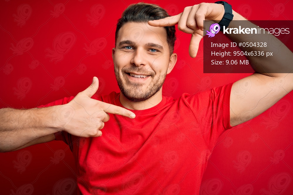 Young man with blue eyes wearing casual t-shirt over red isolated background smiling making frame with hands and fingers with happy face. Creativity and photography concept.