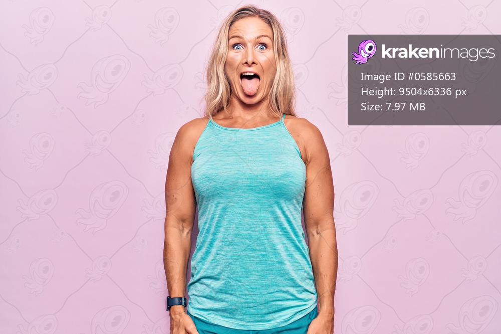 Middle age caucasian blonde woman wearing sports clothes over pink background sticking tongue out happy with funny expression. emotion concept. 