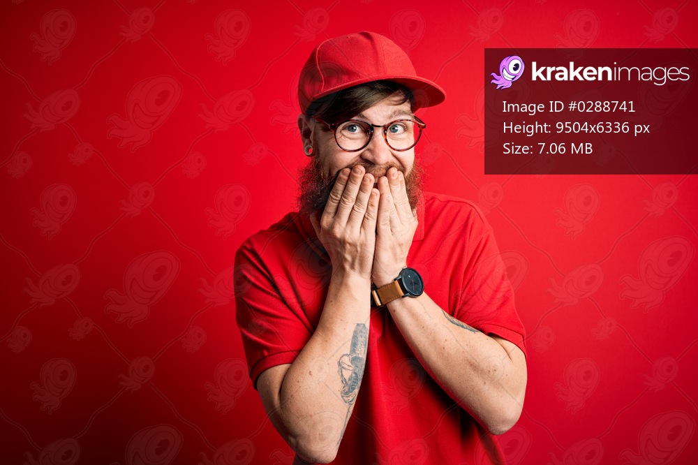 Young handsome delivery man wearing glasses and red cap over isolated background laughing and embarrassed giggle covering mouth with hands, gossip and scandal concept