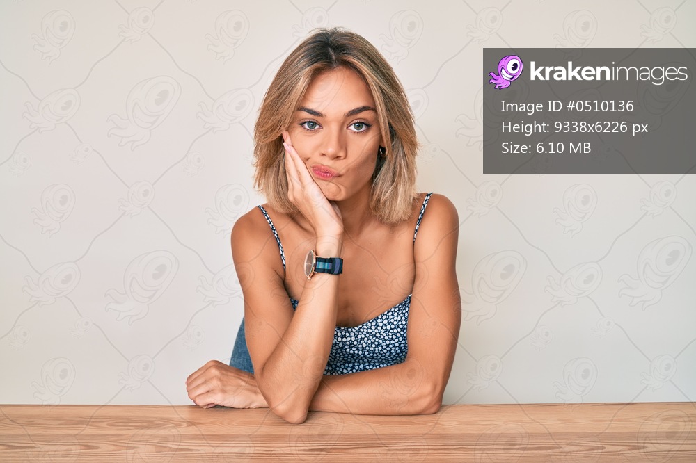 Beautiful caucasian woman wearing casual clothes sitting on the table thinking looking tired and bored with depression problems with crossed arms. 