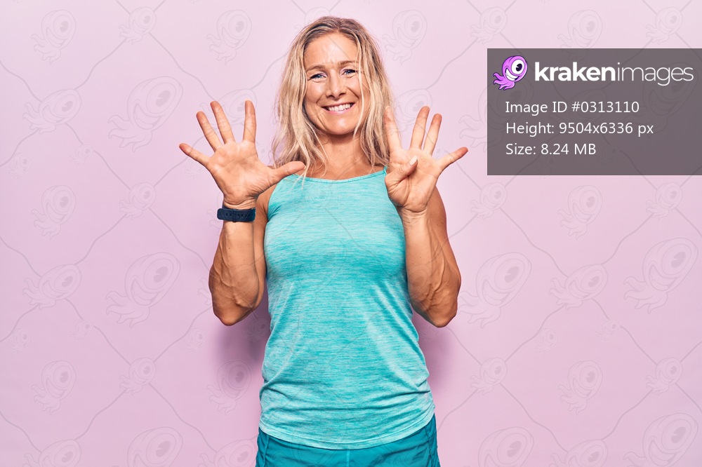 Middle age caucasian blonde woman wearing sports clothes over pink background showing and pointing up with fingers number nine while smiling confident and happy. 