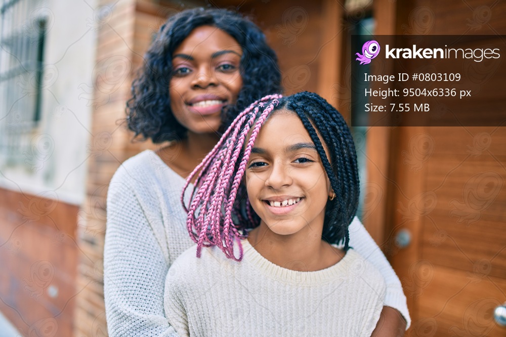 Beautiful african american mother and daughter smiling happy and hugging. Standing with smile on face standing at the city.