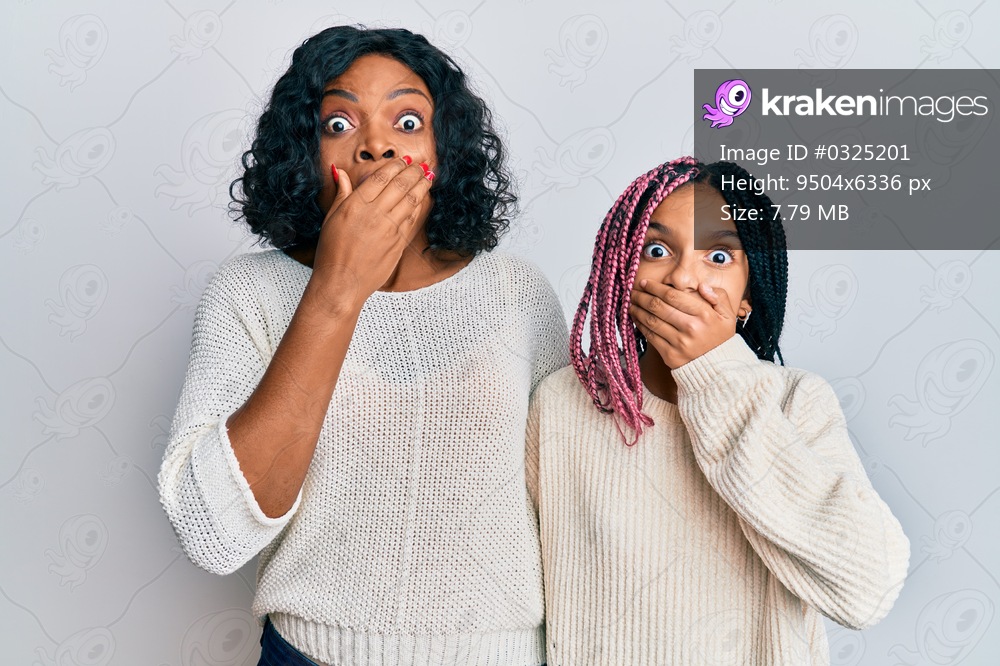Beautiful african american mother and daughter wearing casual clothes and hugging shocked covering mouth with hands for mistake. secret concept. 