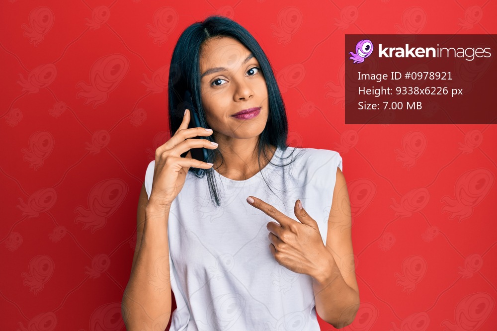 Young african american woman having conversation talking on the smartphone smiling happy pointing with hand and finger 