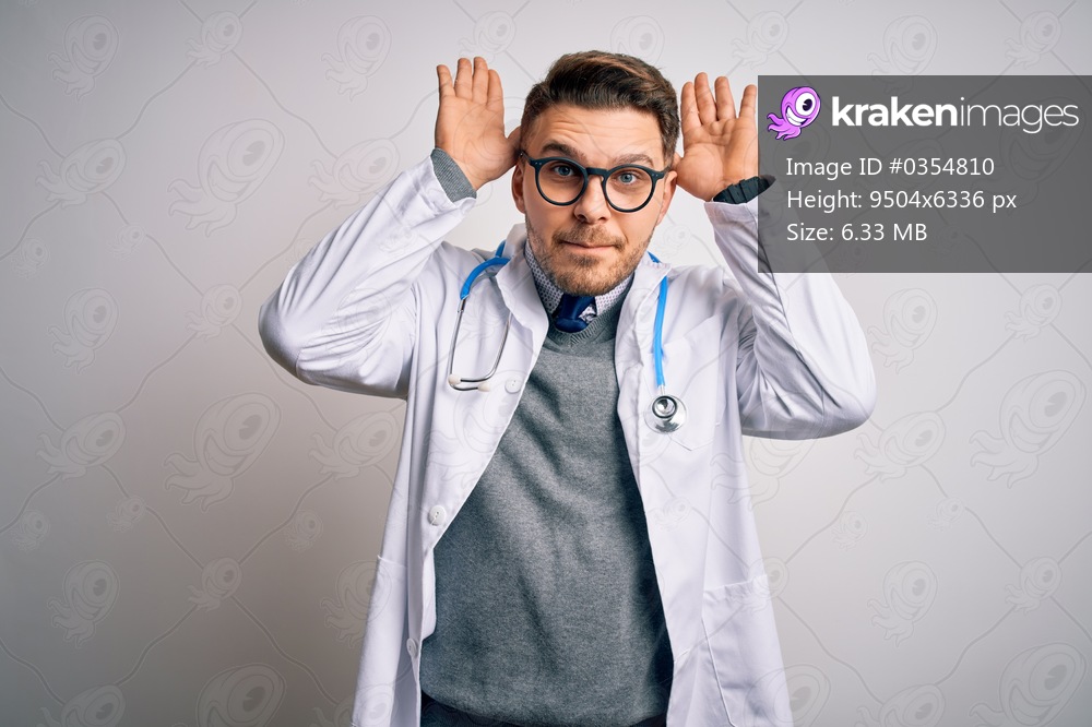 Young doctor man with blue eyes wearing medical coat and stethoscope over isolated background Doing bunny ears gesture with hands palms looking cynical and skeptical. Easter rabbit concept.