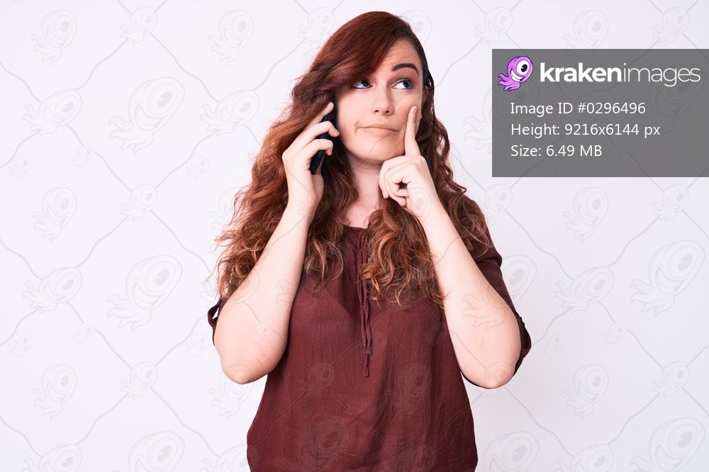Young beautiful woman having conversation talking on the smartphone serious face thinking about question with hand on chin, thoughtful about confusing idea 