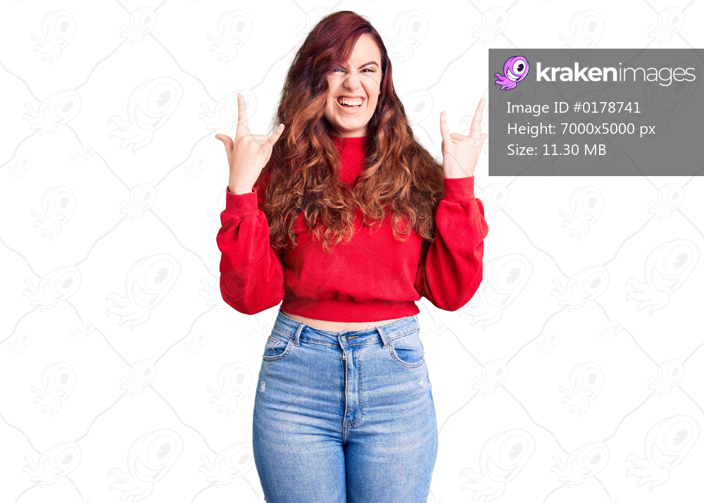 Young beautiful woman wearing casual winter sweater shouting with crazy expression doing rock symbol with hands up. music star. heavy concept. 