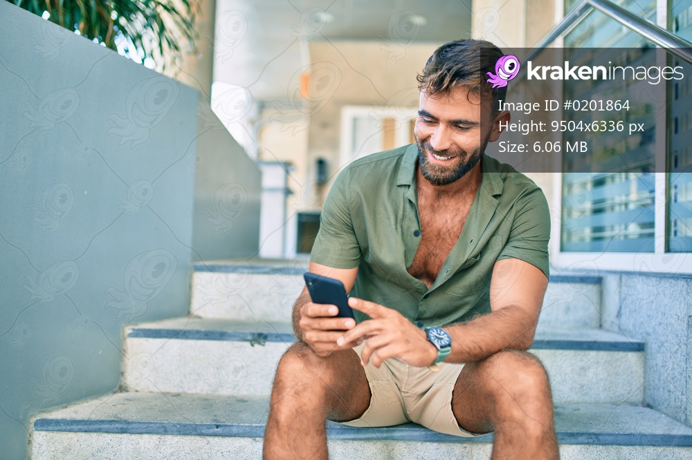 Young hispanic man smiling happy using smartphone sitting on stairs