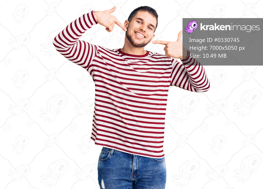 Young handsome man wearing striped sweater smiling cheerful showing and pointing with fingers teeth and mouth. dental health concept. 