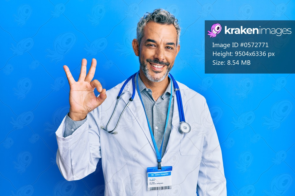 Middle age grey-haired man wearing doctor uniform and stethoscope smiling positive doing ok sign with hand and fingers. successful expression. 
