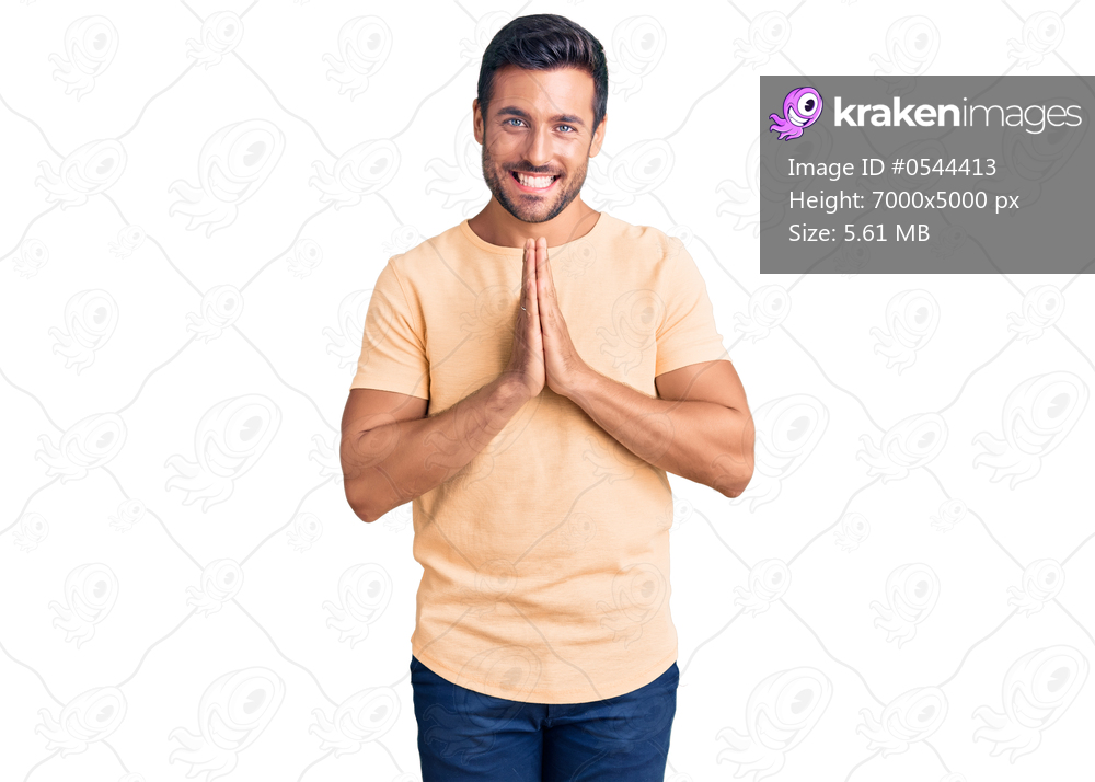 Young hispanic man wearing casual clothes praying with hands together asking for forgiveness smiling confident. 