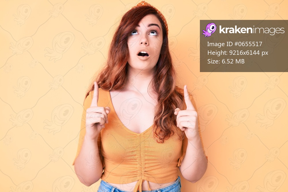 Young beautiful woman wearing casual clothes amazed and surprised looking up and pointing with fingers and raised arms. 