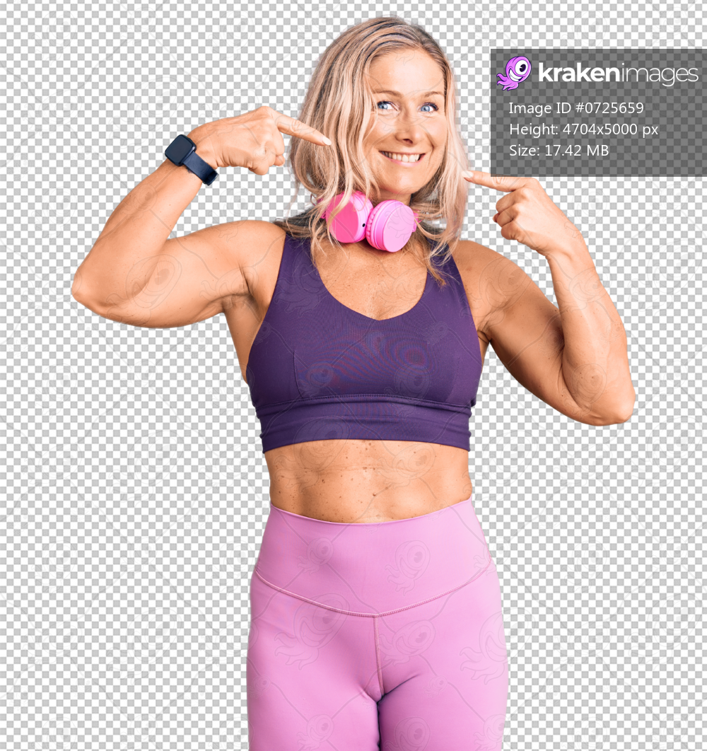 Middle age fit blonde woman wearing gym clothes and using headphones smiling cheerful showing and pointing with fingers teeth and mouth. dental health concept.