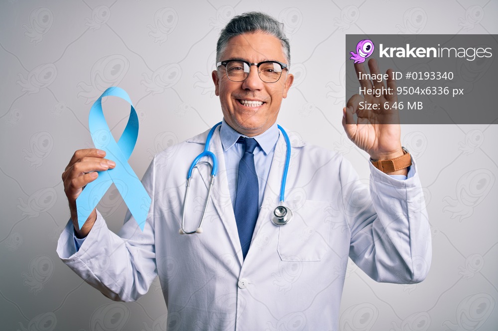 Middle age handsome grey-haired doctor man wearing coat holding blue cancer ribbon doing ok sign with fingers, excellent symbol