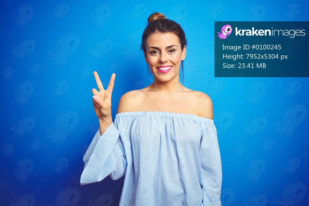 Young beautiful woman wearing bun hairstyle over blue isolated background showing and pointing up with fingers number two while smiling confident and happy.