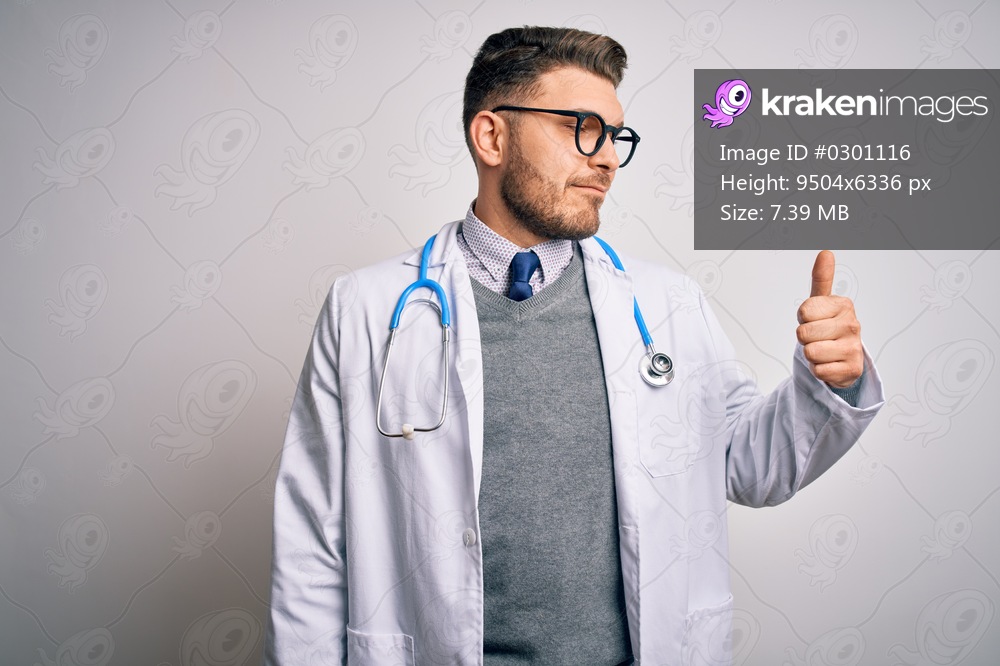 Young doctor man with blue eyes wearing medical coat and stethoscope over isolated background Looking proud, smiling doing thumbs up gesture to the side