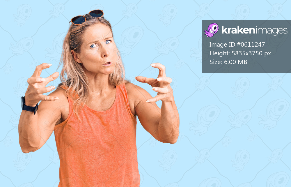 Middle age fit blonde woman wearing casual summer clothes and sunglasses shouting frustrated with rage, hands trying to strangle, yelling mad 