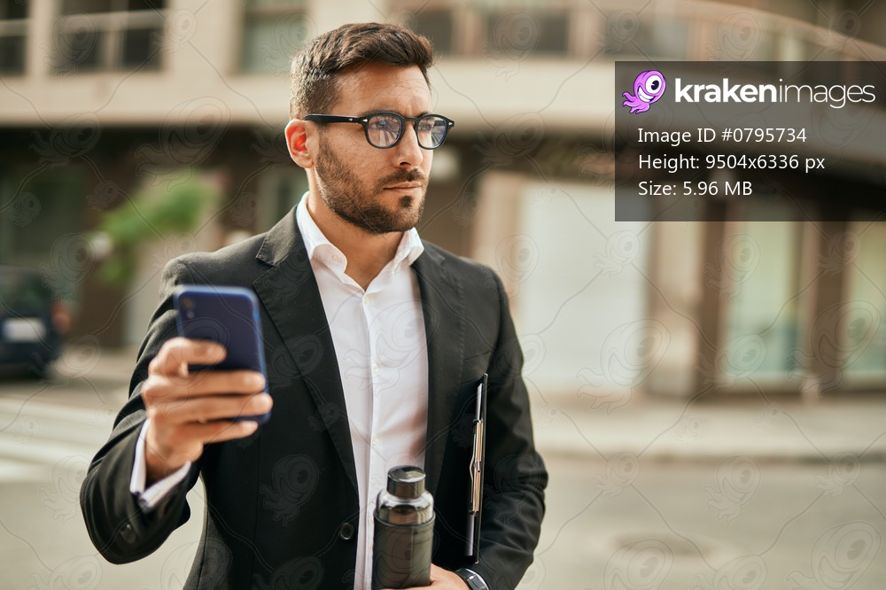 Young hispanic businessman with serious expression using smartphone at the city.