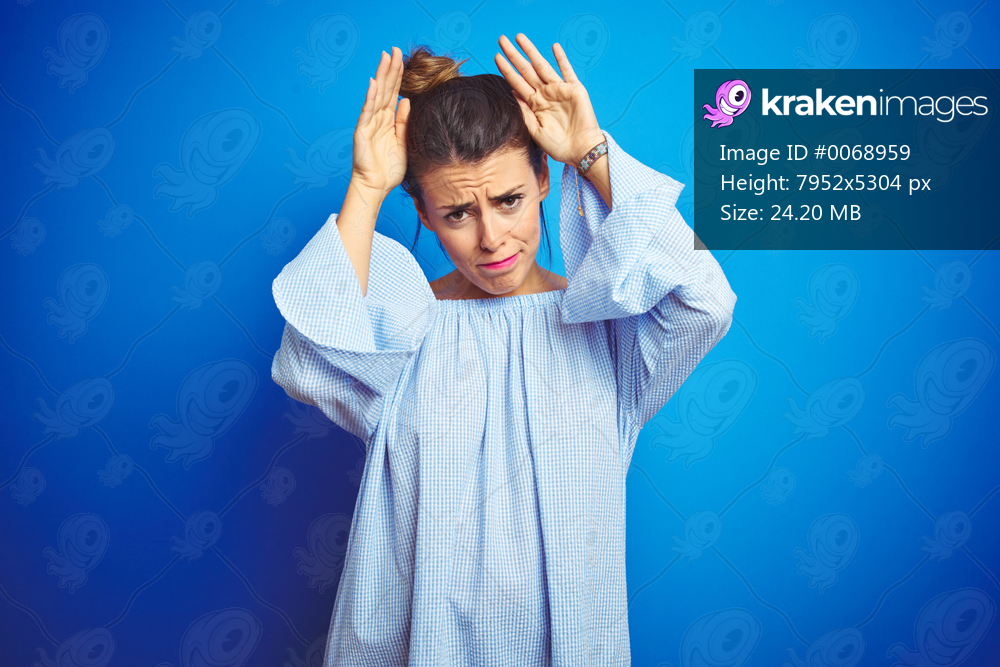 Young beautiful woman wearing bun hairstyle over blue isolated background Doing bunny ears gesture with hands palms looking cynical and skeptical. Easter rabbit concept.