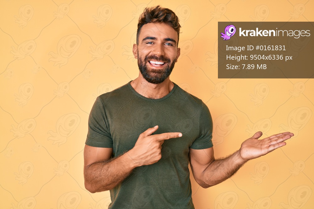 Young hispanic man wearing casual clothes amazed and smiling to the camera while presenting with hand and pointing with finger. 