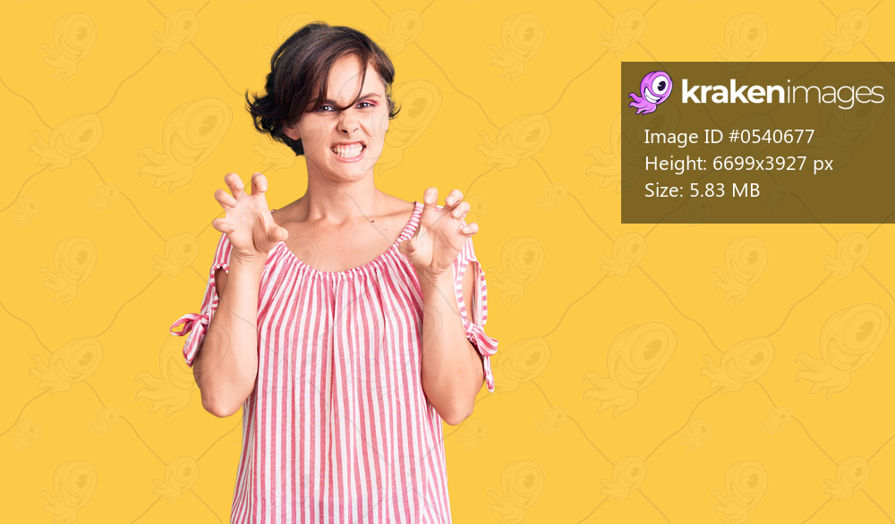 Beautiful young woman with short hair wearing casual summer clothes smiling funny doing claw gesture as cat, aggressive and sexy expression 