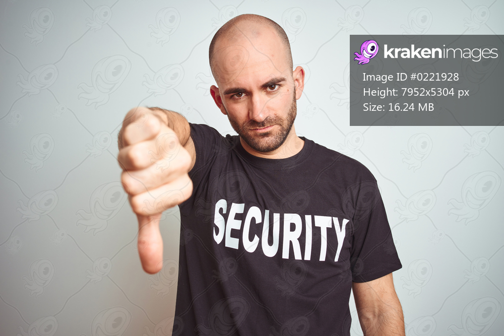 Young safeguard man wearing security uniform over isolated background looking unhappy and angry showing rejection and negative with thumbs down gesture. Bad expression.