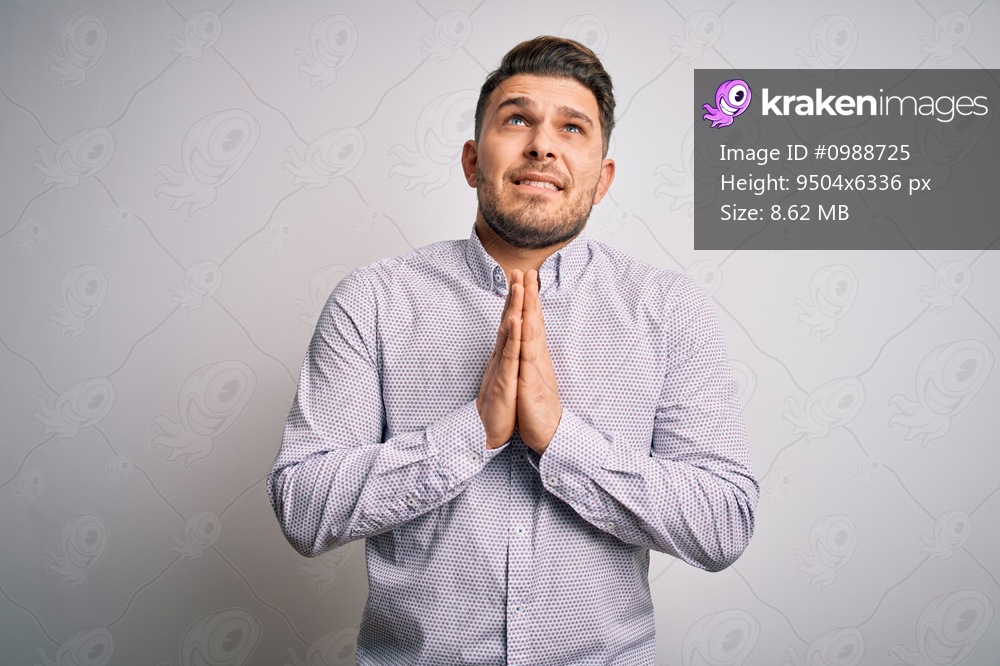 Young business man with blue eyes standing over isolated background begging and praying with hands together with hope expression on face very emotional and worried. Begging.