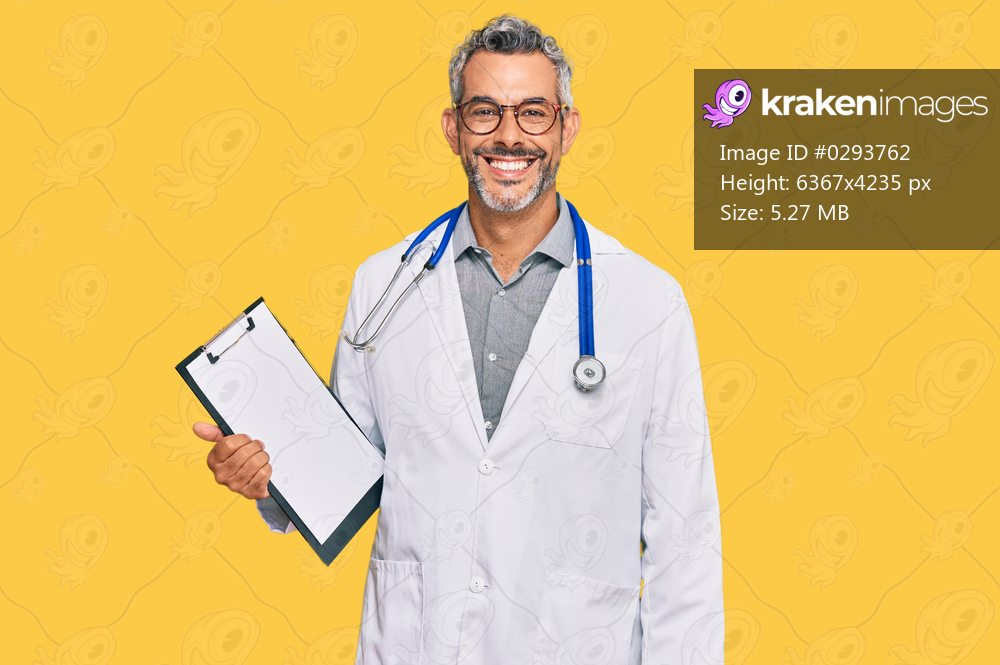 Middle age grey-haired man wearing doctor stethoscope holding clipboard looking positive and happy standing and smiling with a confident smile showing teeth 