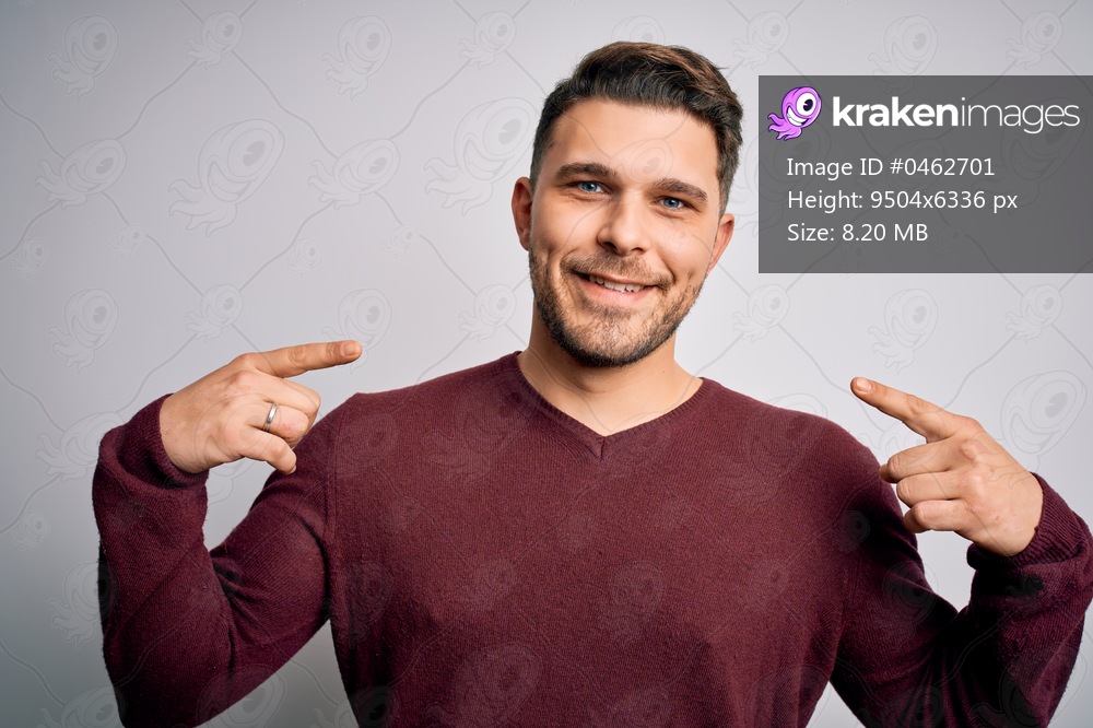 Young man with blue eyes wearing casual sweater standing over isolated background looking confident with smile on face, pointing oneself with fingers proud and happy.