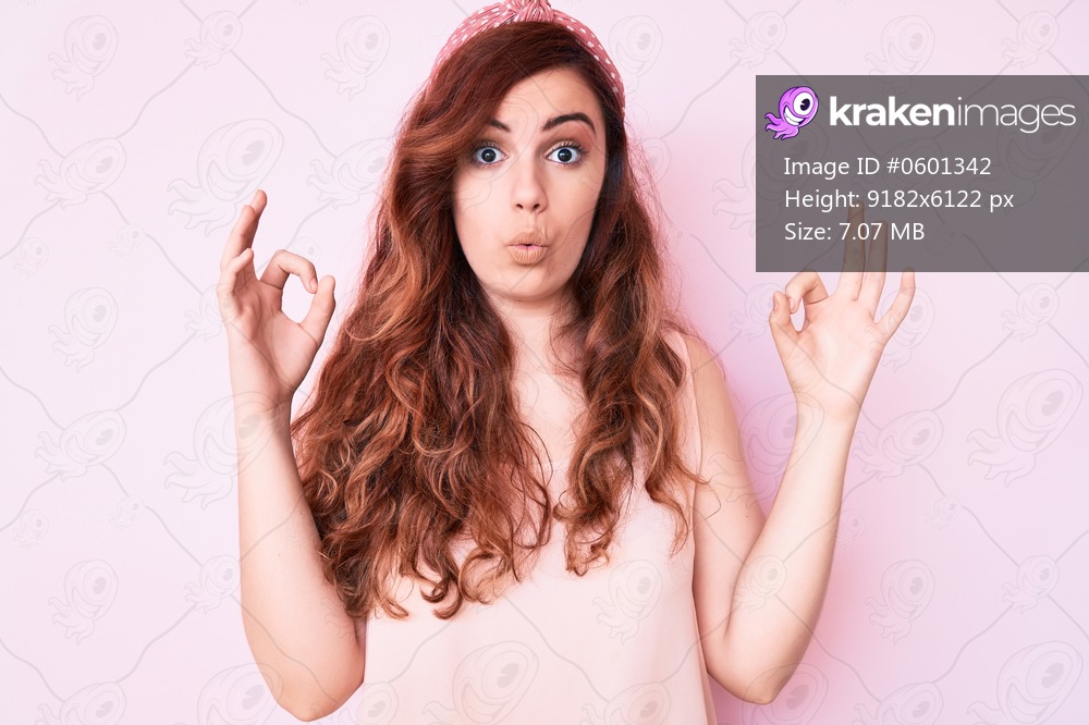 Young beautiful woman wearing casual clothes looking surprised and shocked doing ok approval symbol with fingers. crazy expression 