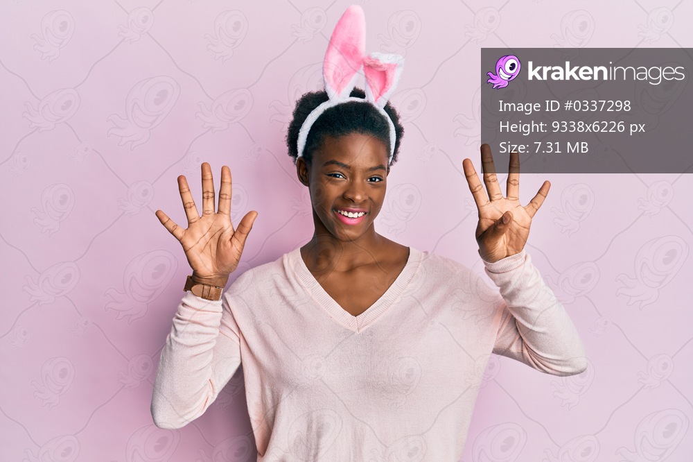 Young african american girl wearing cute easter bunny ears showing and pointing up with fingers number nine while smiling confident and happy. 
