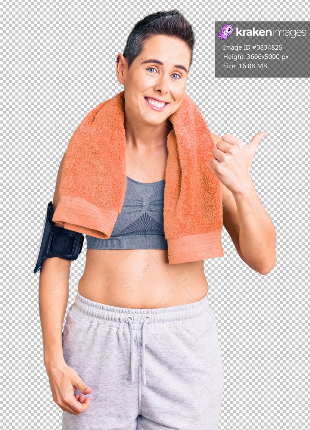 Young woman with short hair wearing sportswear and towel using smartphone smiling with happy face looking and pointing to the side with thumb up.