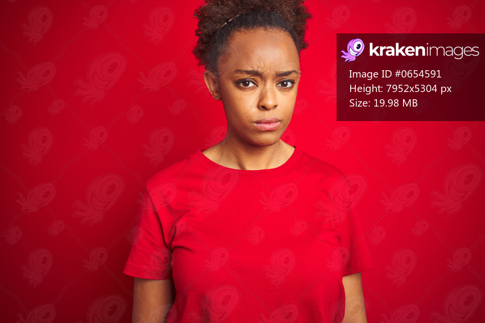 Young beautiful african american woman with afro hair over isolated red background skeptic and nervous, frowning upset because of problem. Negative person.