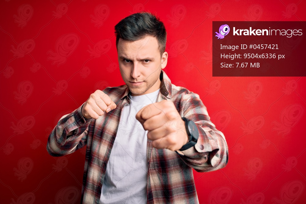 Young handsome caucasian man wearing casual modern shirt over red isolated background Punching fist to fight, aggressive and angry attack, threat and violence