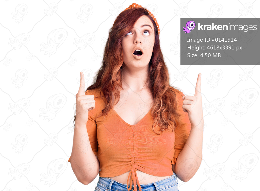 Young beautiful woman wearing casual clothes amazed and surprised looking up and pointing with fingers and raised arms. 